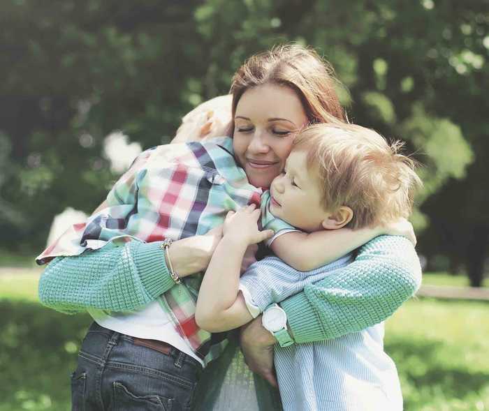 Eine Mutter umarmt ihre beiden Kinder