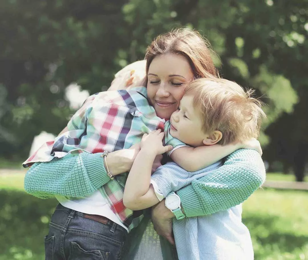 Eine Mutter umarmt ihre beiden Kinder